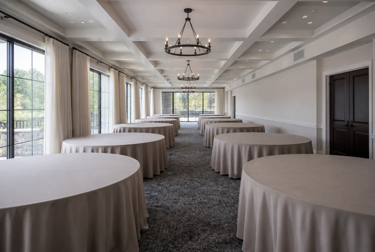 The same long narrow function room set with 72-inch round tables that visibly consume more of the width with same daylight.
