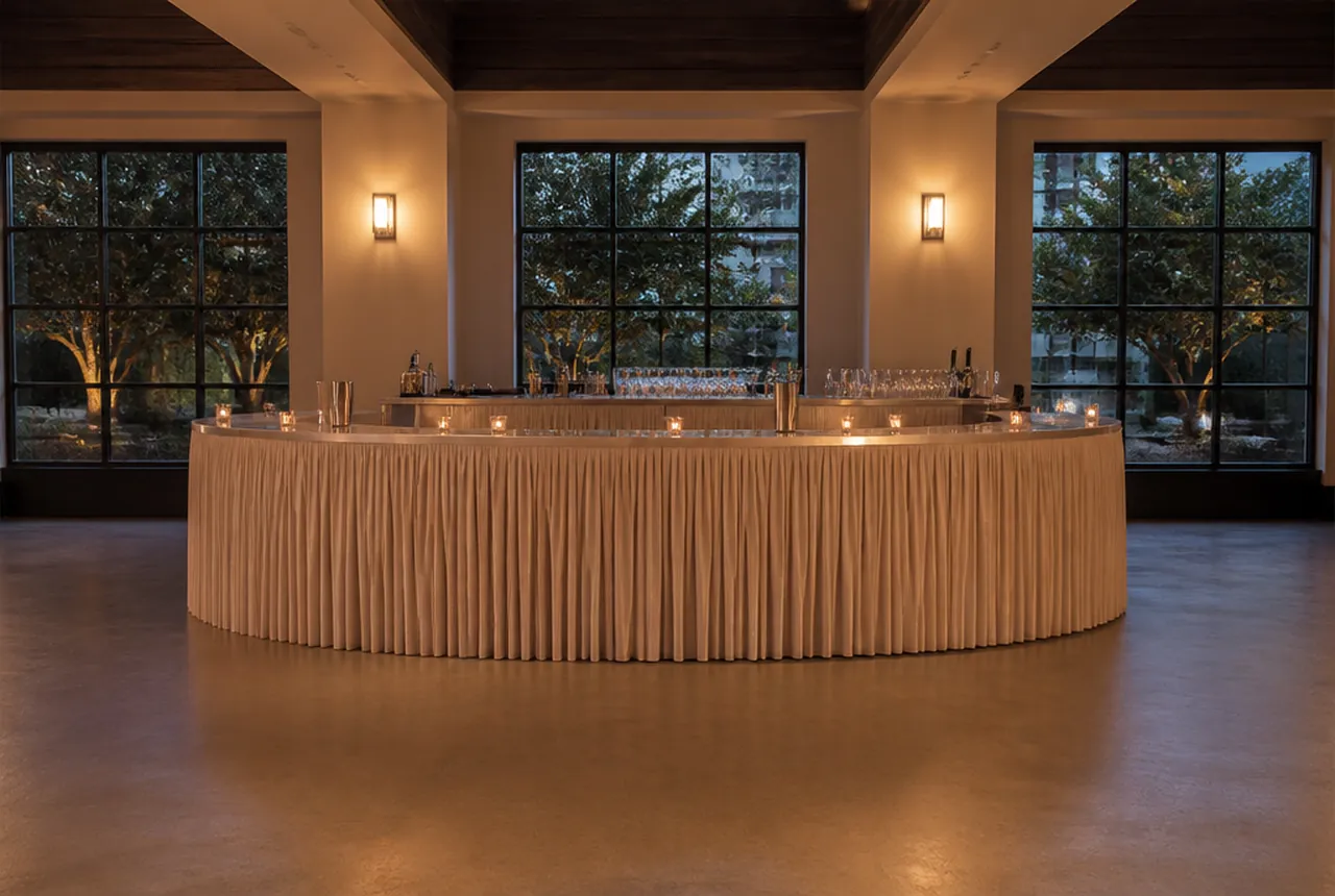 A freestanding skirted portable bar with open floor in front of it and clear working space behind with evening lighting.
