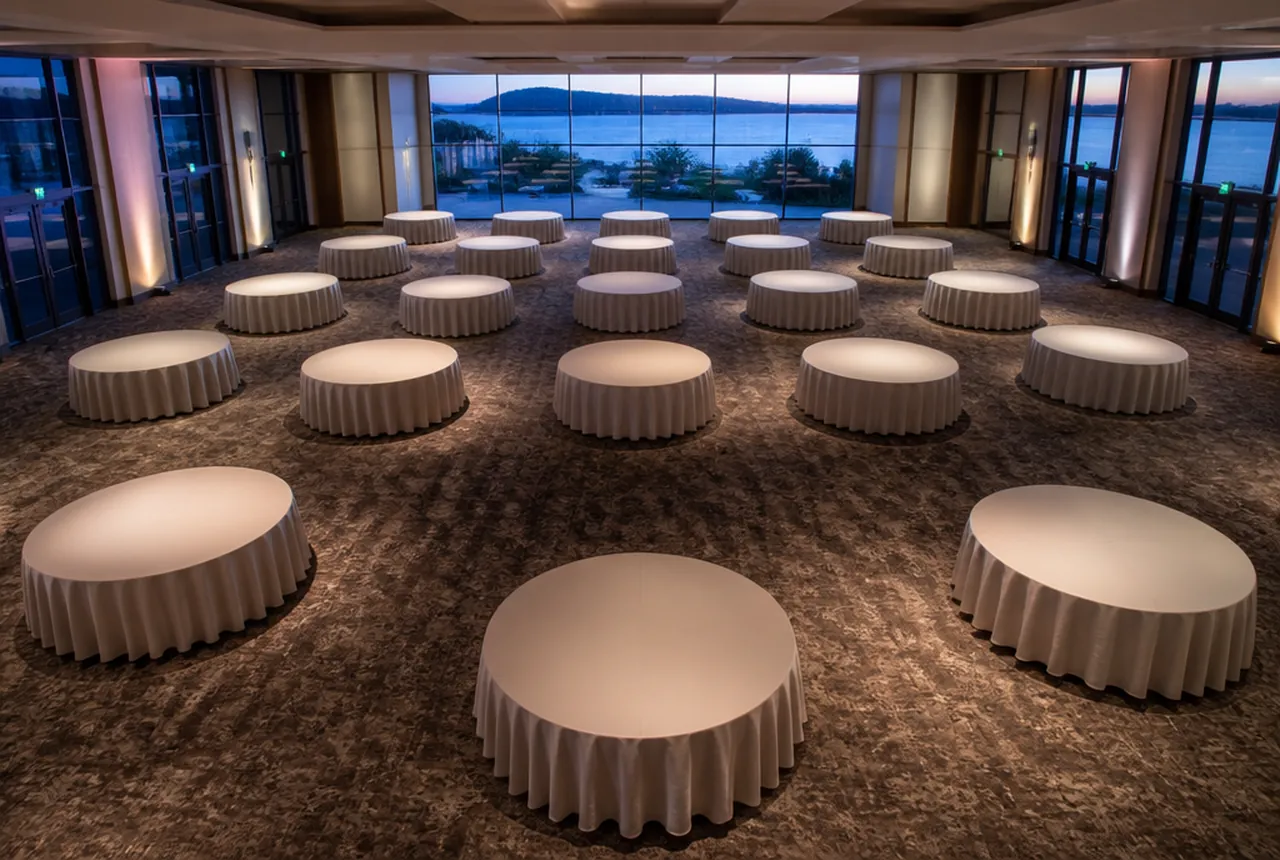 A hall set with 72-inch round tables at even spacing with evening light.
