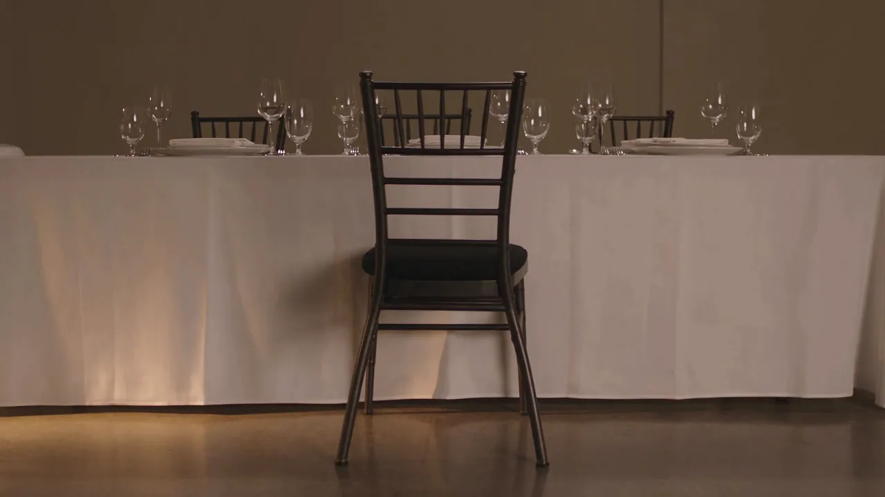 A dark ladder-back chair facing a linen-covered table set with glasses