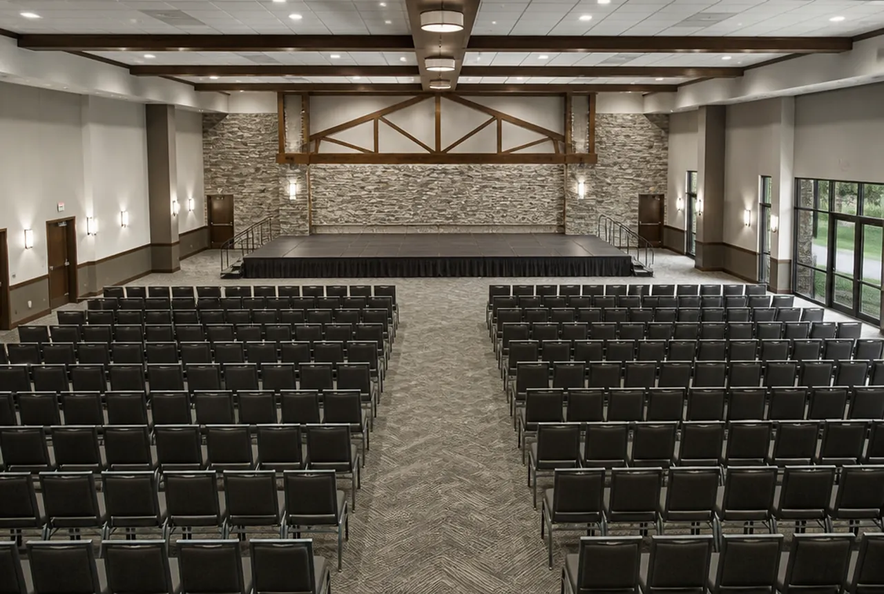 Theater style rows of chairs with no tables, broken by a centre aisle and a cross aisle part way back