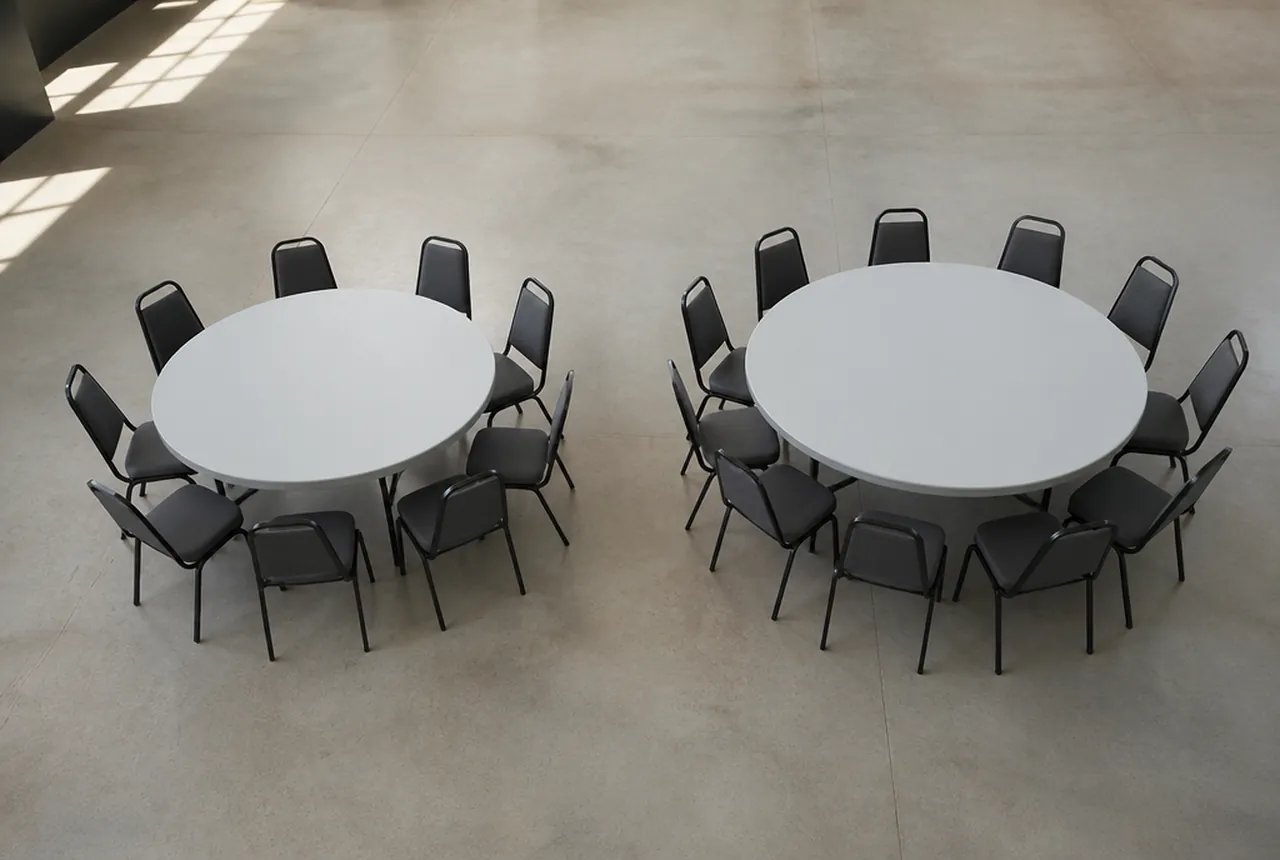 Two bare round banquet tables side by side, one ringed with eight chairs and the other with ten