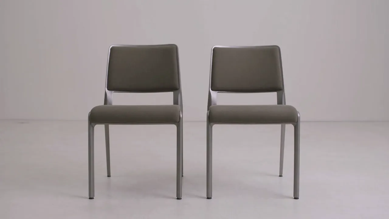 Two grey upholstered chairs standing side by side against a plain background